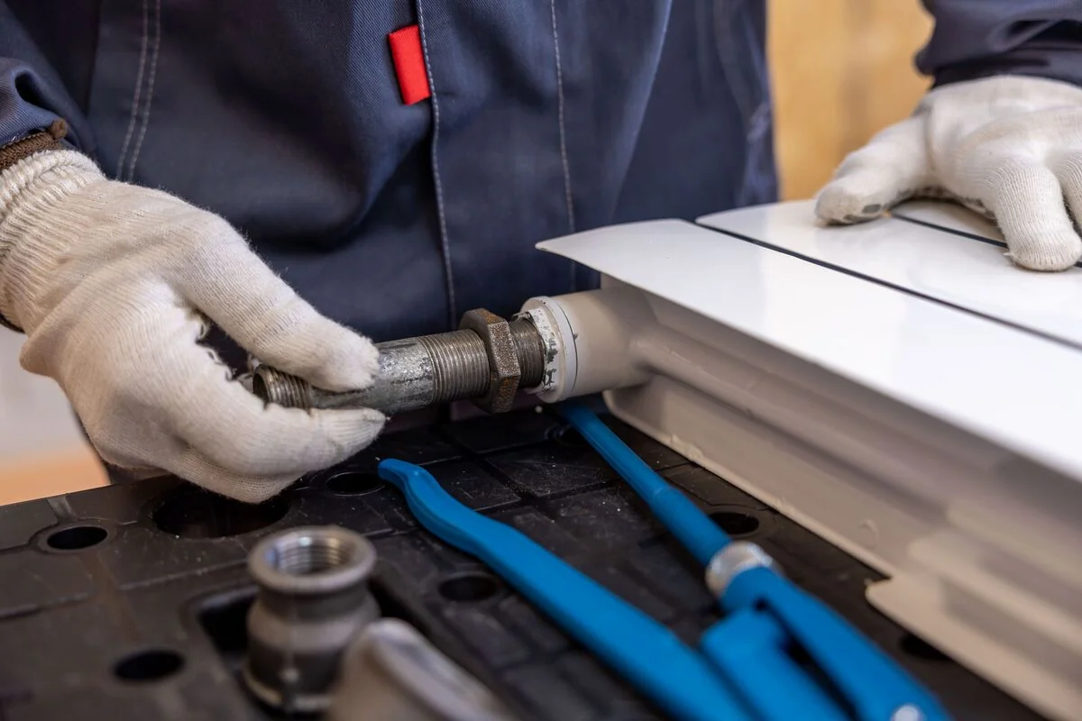 Black plumber repairing pipes during a plumbing installation job