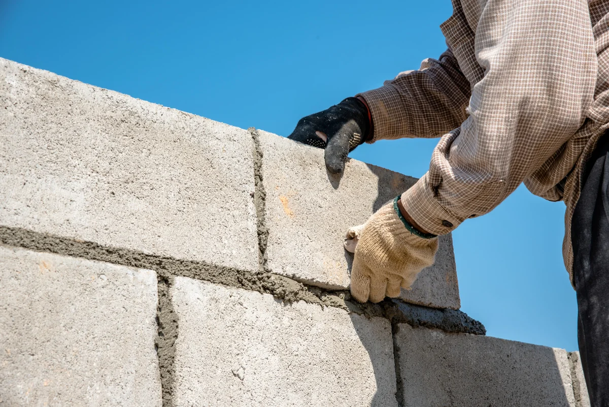 Black construction worker building a residential house with brickwork in progress